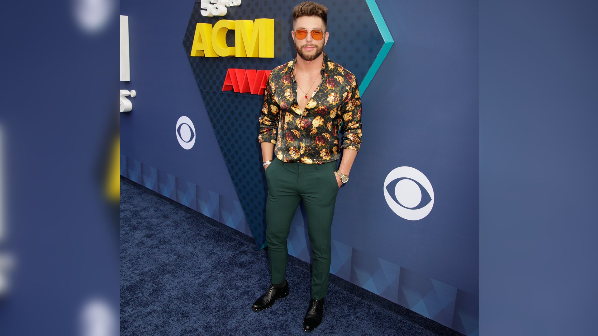 Chris Lane struts down the red carpet in a pair of emerald pants and patterned button-down shirt.