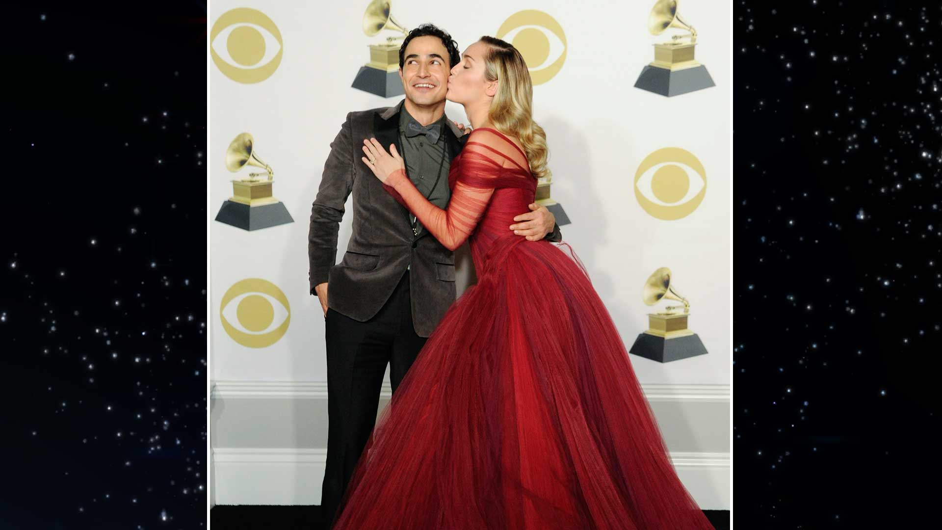 Fashion designer Zac Posen gets a kiss on the cheek from performer Miley Cyrus in the 60th Annual GRAMMY Awards press room. 