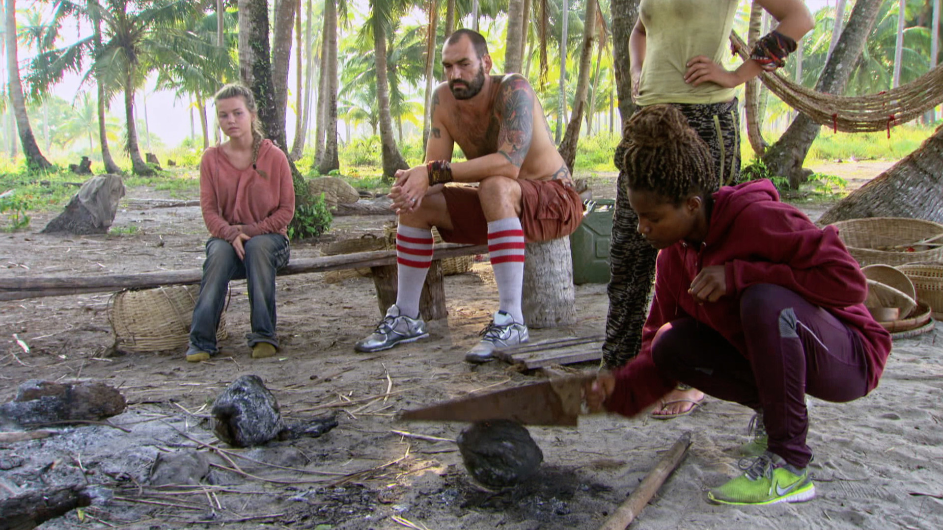 Julia and Scot watch Cydney as she cracks open a coconut.