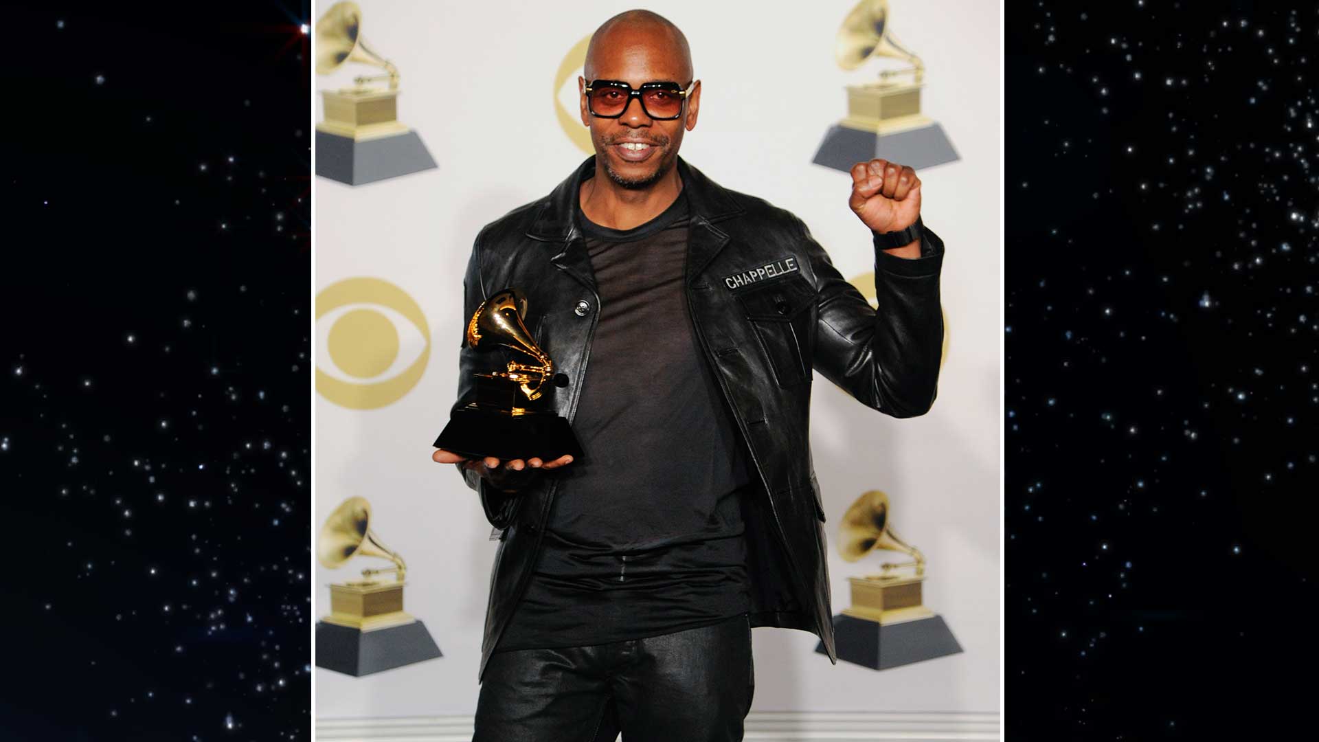 Comedian and Best Comedy Album winner Dave Chapelle throws a triumphant fist in the air.