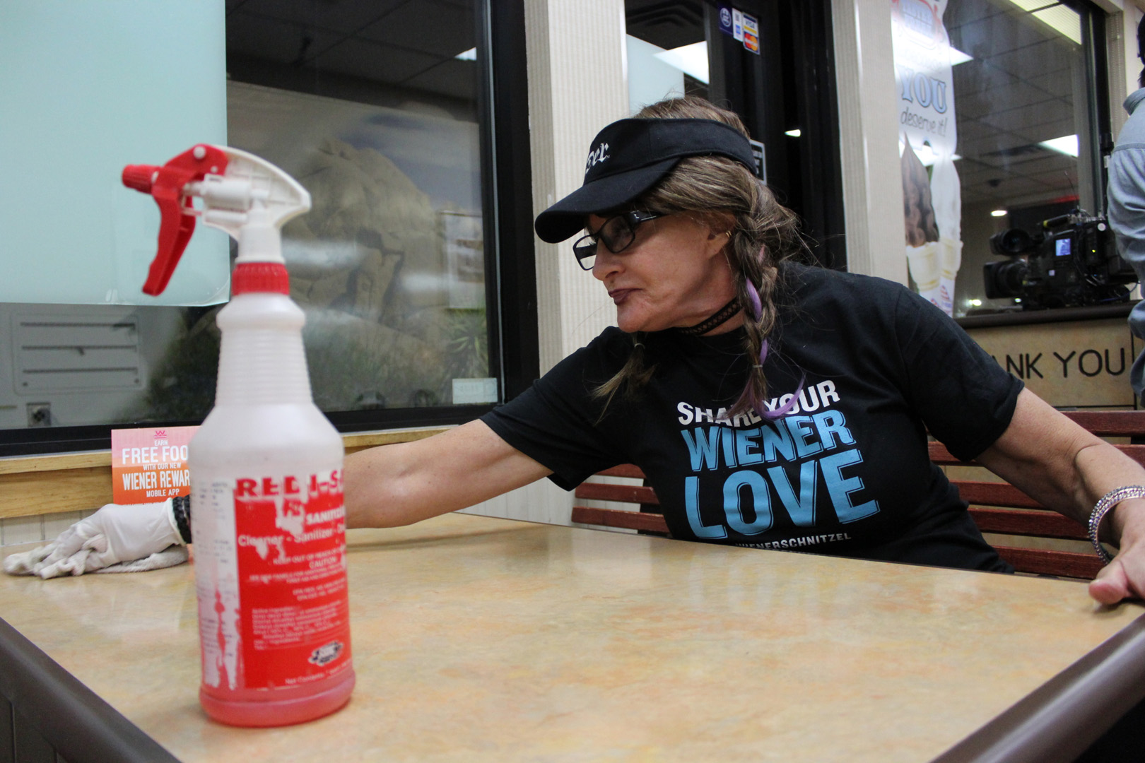 Cynthia wipes down a table while undercover at a Wienerschnitzel location.