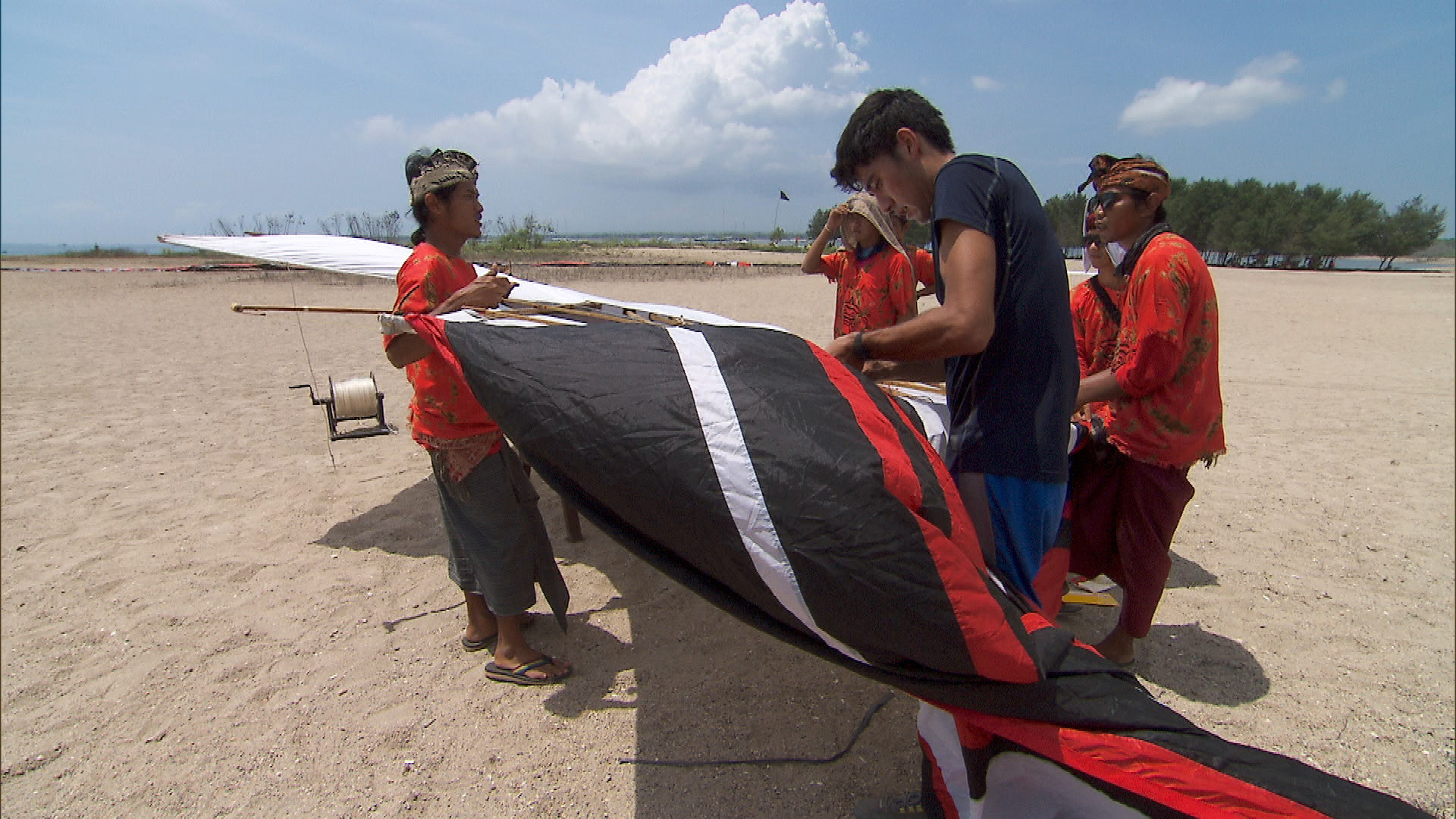 At the second Roadblock, Zach tries to help build and successfully fly a kite.